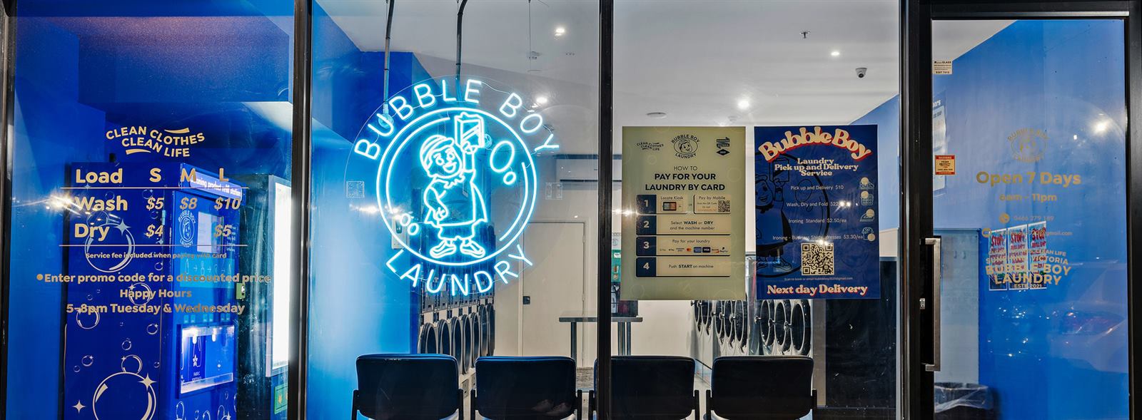 The shopfront at night, the Bubble Boy neon sign glowing cyan in the window with prices on the glass